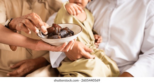 Close-up of hands sharing dates, symbolizing hospitality and tradition. A muslim family gathering, sharing dates, and cultural tradition in focus. Muslim family eating dates at end of Ramadan feast.