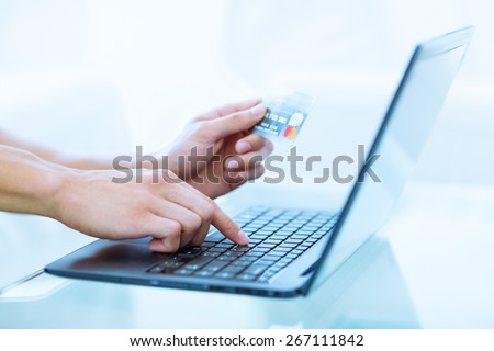 Close-up of hands shopping/paying online using laptop and credit card.