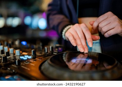 close-up of hands skillfully adjusting knobs and sliders on a professional DJ mixer, illuminated by colorful lights. The mood conveys focus and control during a live music event - Powered by Shutterstock
