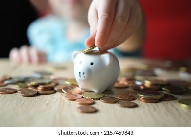 close-up of hands of small child manipulate with metal coins, kid counts, puts euro union money in white piggy bank, concept of pocket money, life insurance, save up for gift, foreground focus - Shutterstock ID 2157459843