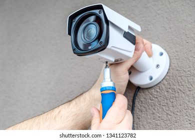Close-up hands of technician adjusting CCTV camera on wall