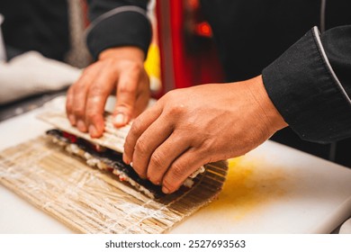 Close-up of a chef’s hands tightly rolling sushi using a bamboo mat. Perfect for sushi-making tutorials, culinary education, or food industry content. - Powered by Shutterstock