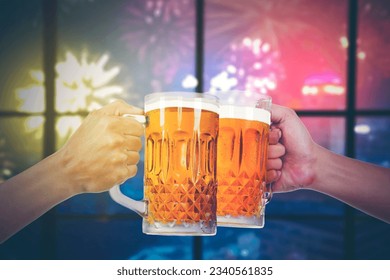 Closeup of hands toasting with bottles of beer at the party club with fireworsk display outside