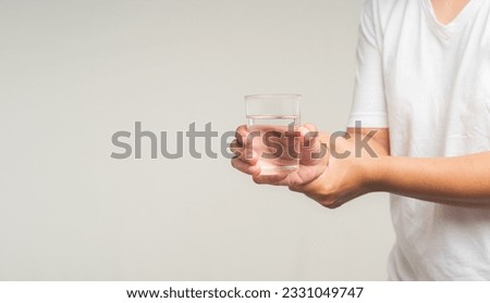 Close-up of hands trying to hold a glass of water. Causes of handshaking include Parkinson's disease, stroke, or brain injury. Mental health neurological disorder