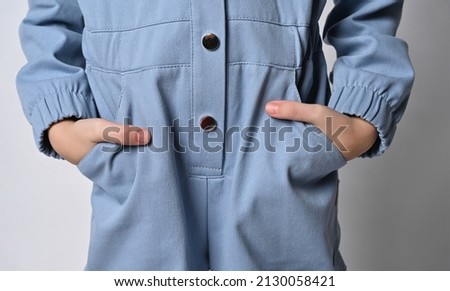 close-up of hands tucked into the pockets of casual cotton overalls. Fragment of a photograph of a child in trousers, isolated on a gray background. Advertisement for children's clothing.