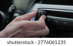 Close-up of hands turning volume button of car radio. Woman driving car. Listen to music while driving