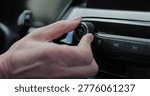 Close-up of hands turning volume button of car radio. Woman driving car. Listen to music while driving