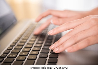 Close-up of hands typing on laptop keyboard in the office.