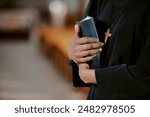 Closeup of hands of unrecognizable African American nun holding Bible book in hands, copy space