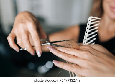 Close-up hands of unrecognizable female hairdresser making stylish haircut with professional scissors to woman client with long blonde hair. Hairstylist cutting lady hair with barber scissors. - Powered by Shutterstock