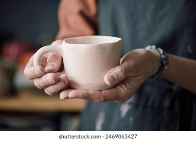 Closeup of hands of unrecognizable female potter holding handmade ceramic cup - Powered by Shutterstock