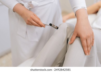 Close-up hands of unrecognizable neurologist doctor checking knee reflex of young female patient using hammer. Process neurological physical examination in clinic. Concept of healthcare and medicare. - Powered by Shutterstock