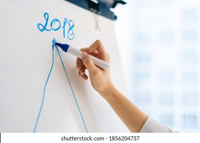 Close-up Hands Of Unrecognizable Young Business Woman Writing On White Board During Presentation In Conference Room. Closeup View Of Arm With Marker And Whiteboard, Writing Business Plan On Flipchart.