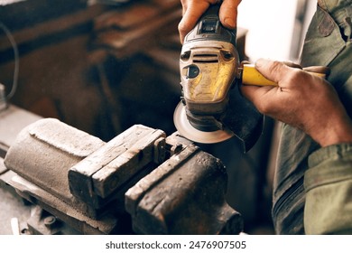 Close-up of hands using an angle grinder on metal at a workbench - Powered by Shutterstock