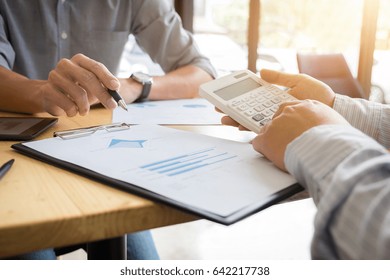 Close-up of hands using calculator, Two business colleague meeting to discussing the business strategy with digital tablet and calculator. Briefing, brainstorming, consulting.