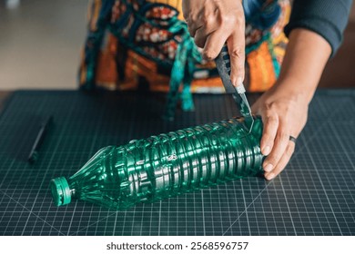 Close-up of hands using cutter on plastic bottle, promoting environmental awareness through reuse and upcycling