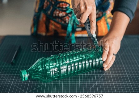 Close-up of hands using cutter on plastic bottle, promoting environmental awareness through reuse and upcycling