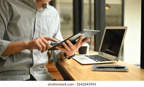 Close-up of hands using a tablet device for creative work in modern workspace.