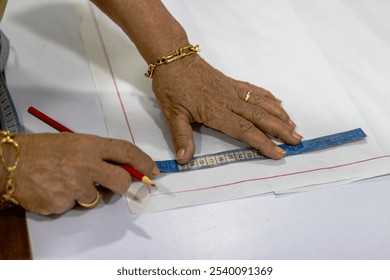 Close-up of hands using a tape measure and pencil to mark fabric for tailoring. This image captures the precision and care involved in pattern making, essential in sewing and fashion design. Ideal  - Powered by Shutterstock