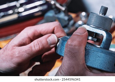 Close-up of watchmaker’s hands using a textured tool on a workbench. The precise grip and firm hold reflect the dexterity essential in handling tiny watch components - Powered by Shutterstock