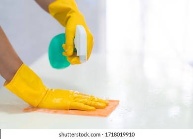 Closeup Hands Wear A Rubber Safety Gloves Is Cleaning The Surface Of Table In The Kitchen With Spray Cleaning Agent And Wet Clothes, Concept Of Surface Cleaning And Hygienic In Covid 19 Outbreak.