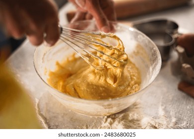 Close-up of hands whisking smooth batter in a glass bowl, preparing dough for baking. The scene captures the texture and motion in a cozy kitchen setting - Powered by Shutterstock