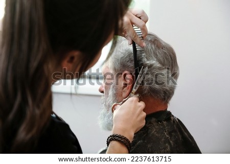 Closeup hands working with hair scissors. Professional hairstyler woman cutting hair of mature man. He is getting haircut at barbershop or beauty salon. Stock foto © 