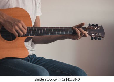 Closeup Of Hands Working On An Instrumental Instrument While Playing And Singing At Home Due To Quarantine. The Sitting Singer Strums The Guitar. To Improve Your Mood.