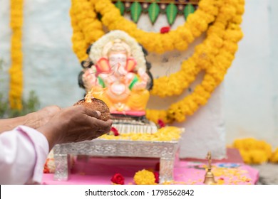 Closeup Of Hands Worshiping Lord Ganesh By Offering Aarti During Vinayaka Chaturthi Festival Pooja Or Puja Celebration At Home In India.