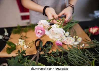 Closeup of hands of young woman florist creating bouquet of pink roses on the table - Shutterstock ID 408278383