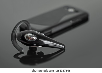 Close-up Of Handsfree Bluetooth Device Near Mobile Phone.