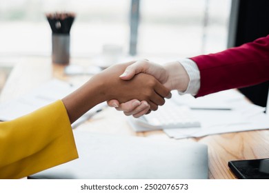 Close-up of a handshake between two professionals in a modern office, symbolizing partnership and agreement.