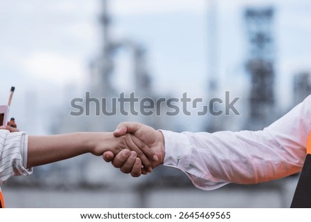 A close-up of a handshake between two professionals at an oil refinery, symbolizing agreement, partnership, or successful negotiation in an industrial and engineering setting.