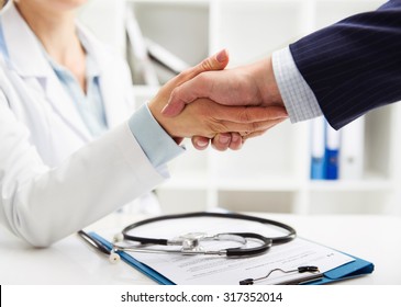 Closeup of handshake of female doctor and businessman over medical form. Concept of health, partnership and  cooperation. 