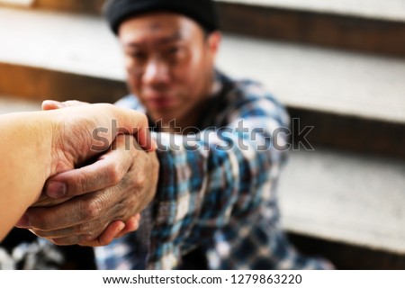 Close-up handshake homeless man on walkway street in the city.
