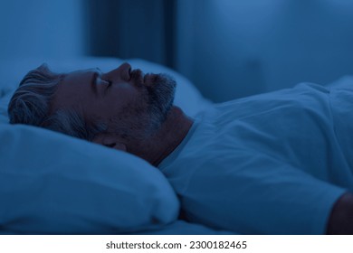 Closeup of handsome grey-haired middle aged man wearing white t-shirt sleeping on back in bed at night at home, side view, copy space. Comfortable healthy sleeping concept - Powered by Shutterstock