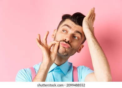 Close-up Of Handsome Man Fixing Haircut And Touching French Moustache, Looking Aside Confident, Standing Over Pink Background