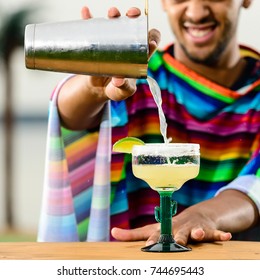 Close-up Of Handsome, Smiling Mexican Bartender Standing On The Bar Counter On The Beach And Adding Some Liquid In A Glass