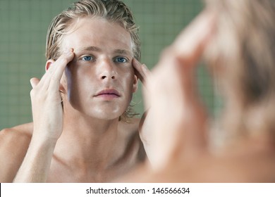 Closeup of handsome young man examining himself in front of mirror - Powered by Shutterstock