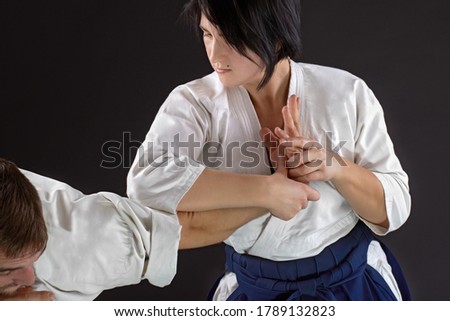 Closeup hand-to-hand man and woman fight on a black background. Asian kung-fu vs European karate School. Training fight concept.