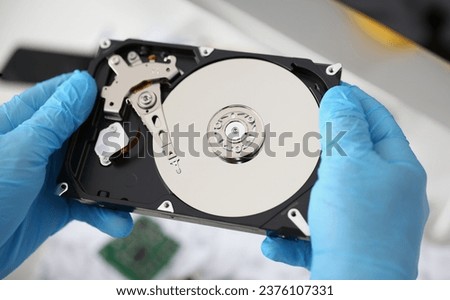 Close-up of handyman hold disassembled hard drive from computer, hdd and reader. Part of computer device, magnetic disc with electronic part. Tech concept