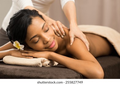 Closeup of happy african woman receiving back massage at salon spa