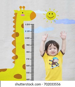 Closeup Happy Asian Kid Stand For Measure Height With Cute Cartoon At The Marble Stone Wall Textured Background In Growth Of Kid Concept