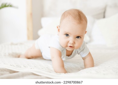 close-up of a happy baby on a white cotton bed in a bright bedroom, a small smiling baby boy or girl crawling - Powered by Shutterstock