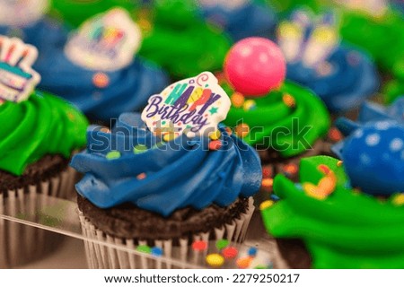 Closeup of Happy Birthday Cupcakes with green and blue frosting, with blue and pink gumboils