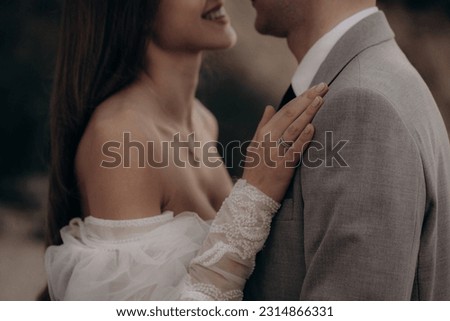 Closeup of happy couple having photoshoot outdoors, kissing. Young groom and bride getting married, smiling, enjoying, having photoshoot. Concept of happiness and family relations.