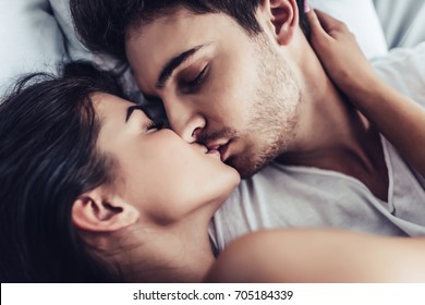 幸せな夫婦の接写が一緒にベッドに横たわっている。キスして楽しみ合って。