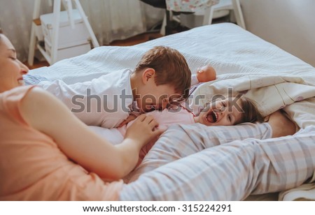 Similar – Relaxed mother and sons playing over the bed