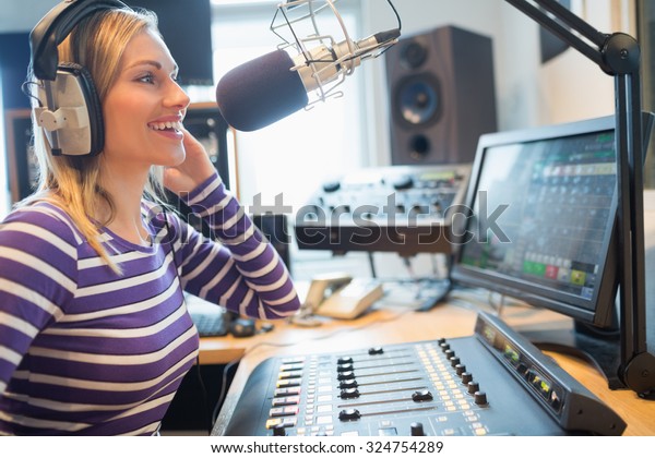 Close-up of happy female radio host broadcasting\
through microphone in\
studio