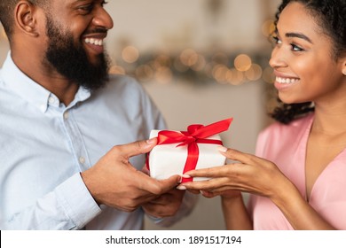 Closeup of happy lovers exchanging gifts on holiday, anniversary, St Valentine's day or birthday. Happy attractive young african american female giving or receiving present surprise from her man - Powered by Shutterstock